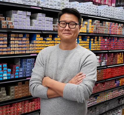 The owner of a beauty supply store that received CDFI financing stands smiling with his arms crossed in his store aisle.