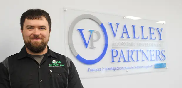 Man standing in front of Valley Partners sign and logo