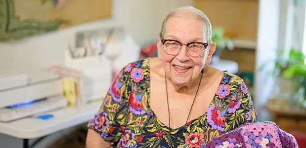 Senior citizen in a colorful dress, smiling.