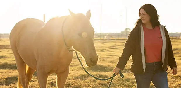 Jessica King walking outside with horse in low sun