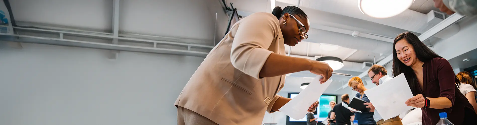 People in suits leaning over table sharing documents