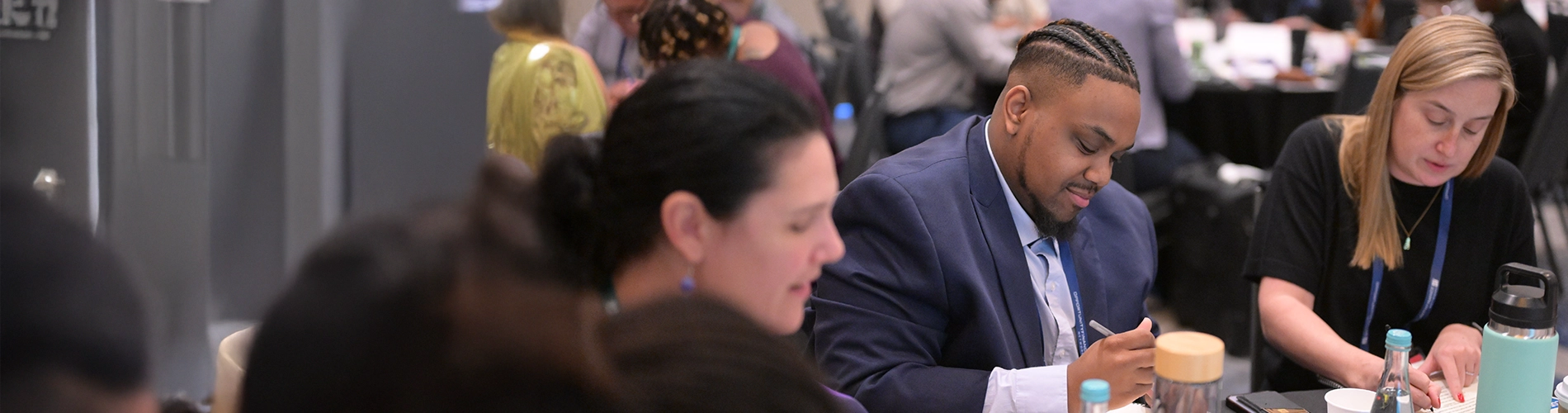 Three people sitting at round table writing