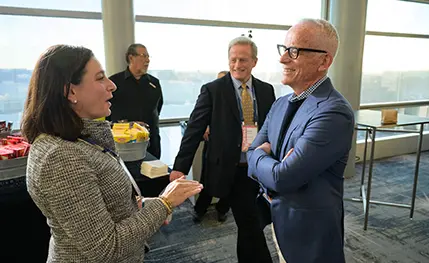 Woman, facing profile, conversing with a be-speckled man who has his arms crossed but is smiling