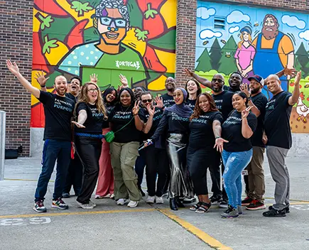 ProsperUs group photo in front of 2 wall murals during a family block party