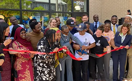 A group of people celebrates the ribbon cutting of Nubian Markets in Roxbury, MA, supported by MHIC.