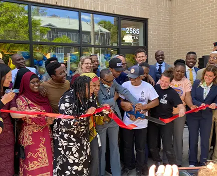 Group photo displaying a ribbon cutting ceremony outside of Nubian Markets