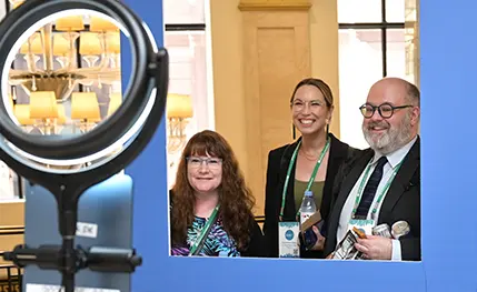 Three people pose at a conference photobooth.