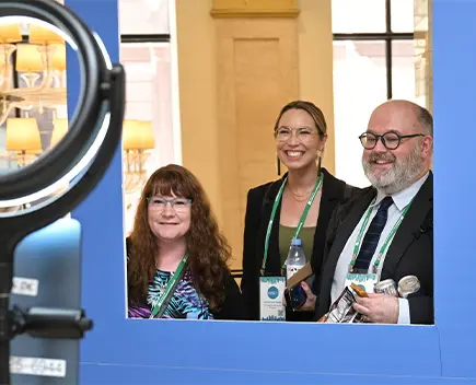 Mirror shot of 3 OFN conference attendees smiling
