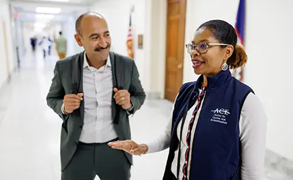 A man and a woman stand talking in the halls of the Capitol.
