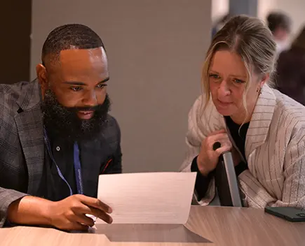 A man and a woman sit at a table and review a document.